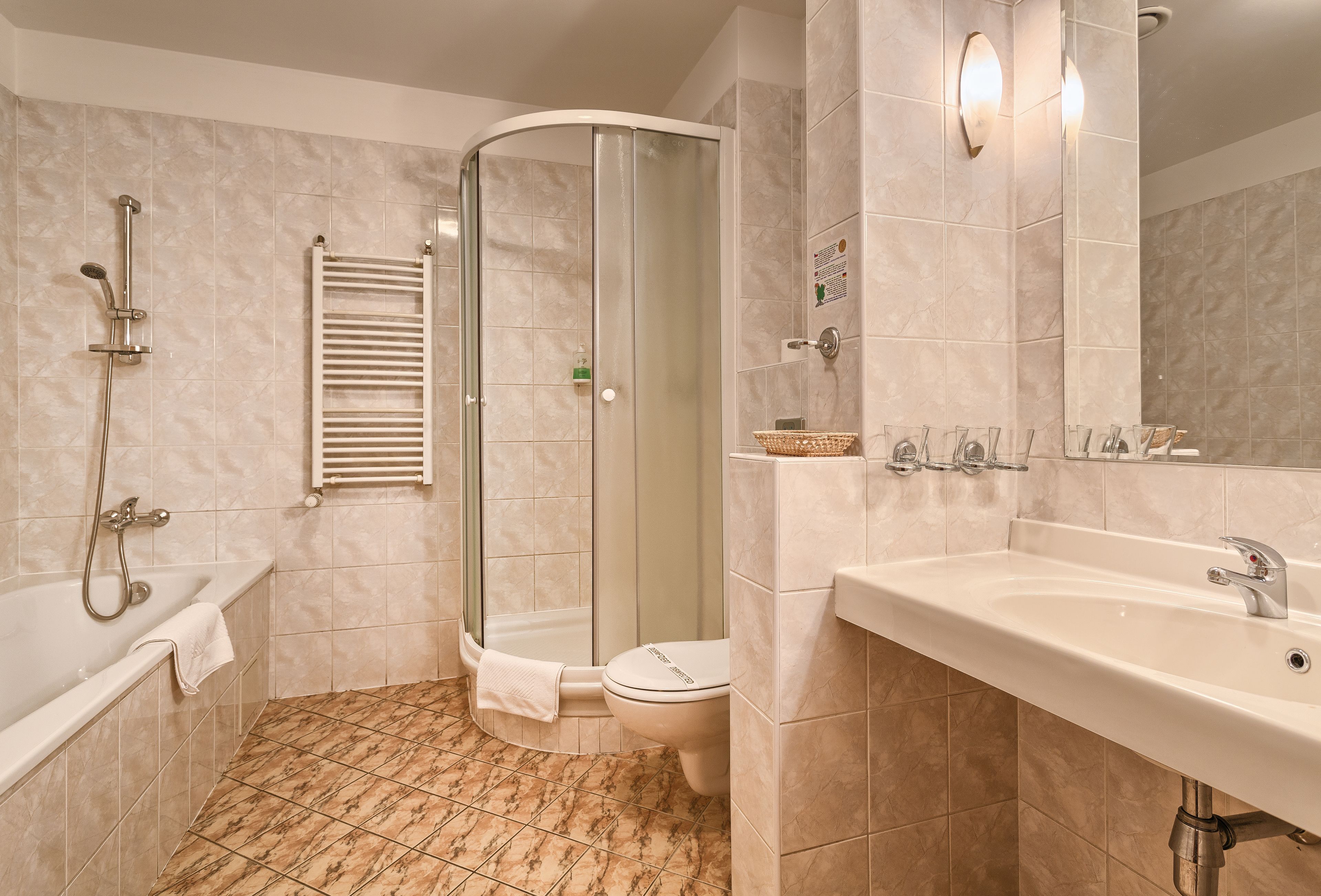 A modern bathroom with a glass-enclosed shower, a bathtub, a toilet, and a sink with a mirror.