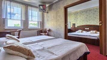 Habitación de hotel con dos camas, una silla de madera, un televisor y un espejo.
