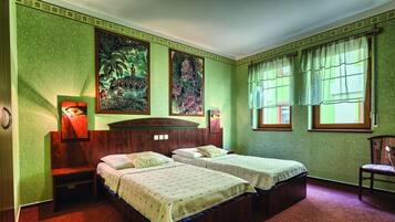 A room with two beds, a wooden headboard, a nightstand, a chair, and two wall-mounted lamps.