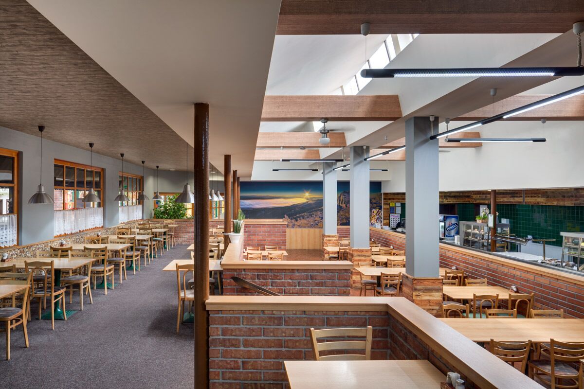 Un restaurante espacioso con techos altos, paredes de ladrillo visto y diferentes opciones de asientos, incluyendo mesas y cabinas.