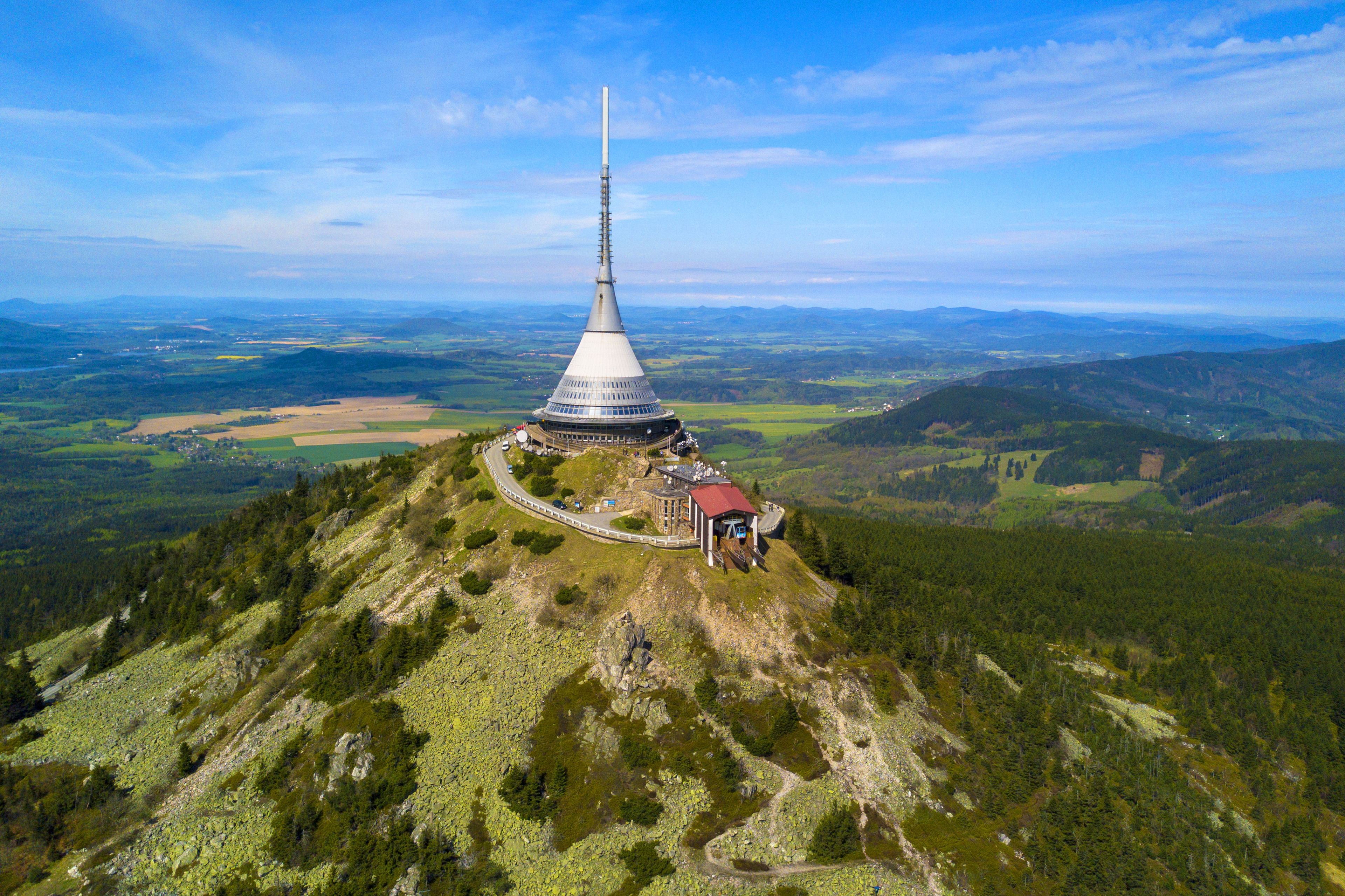 Un observatorio de montaña con una torre alta, rodeado de colinas boscosas y un cielo despejado.