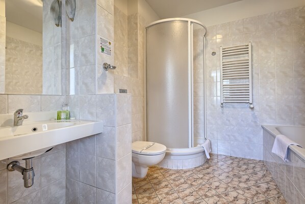 A bathroom with a shower, toilet, sink, and a towel rack.