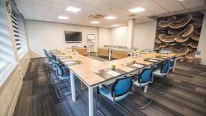 A conference room with a long table, blue chairs, and a projector screen. - Flonk Hotel Groningen Centre, BW Signature Collection (Groningen)