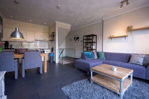 A modern living room with a grey sofa, a coffee table, and a dining area with a table and chairs. - Flonk Hotel Groningen Centre, BW Signature Collection (Groningen)