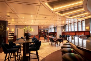 A modern hotel lobby with a bar area, seating arrangements, and a large bookshelf. - Flonk Hotel Groningen Centre, BW Signature Collection (Groningen)