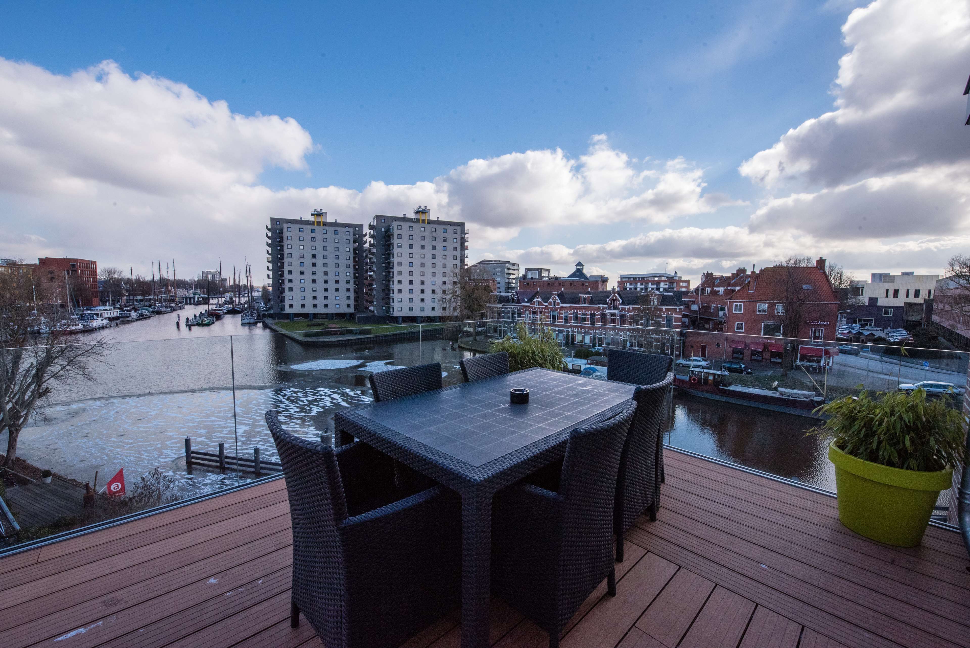 Una terraza con mobiliario exterior con vistas a un canal y edificios.