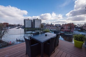Una terraza con mobiliario exterior con vistas a un canal y edificios.