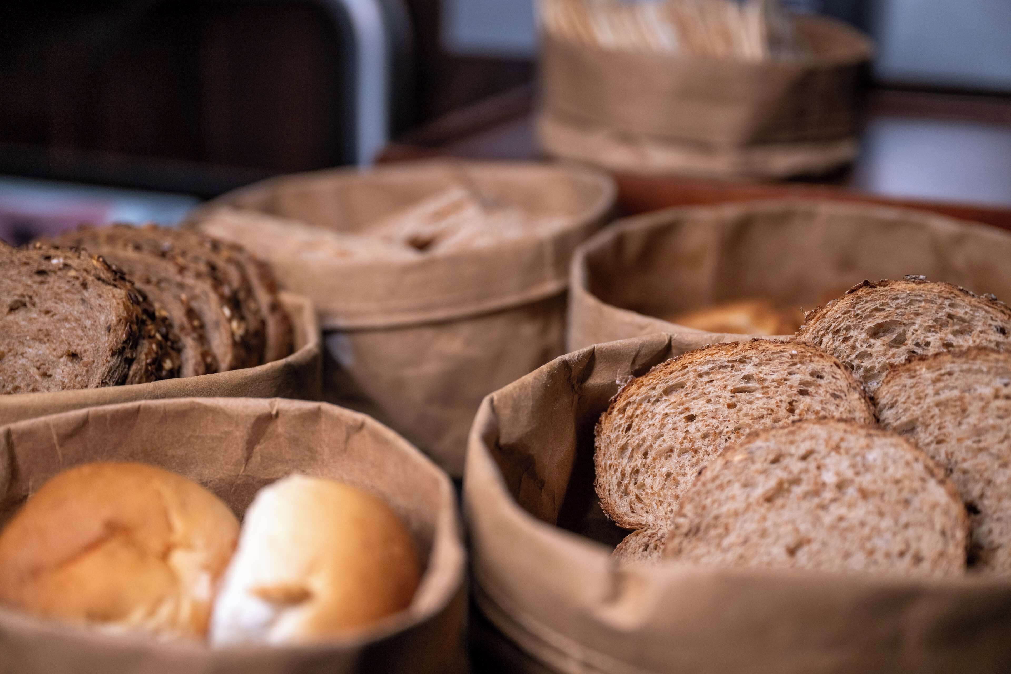 A variety of breads in paper bags on a table.