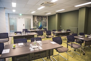 A conference room with tables, chairs, and a peacock mural on the wall.
