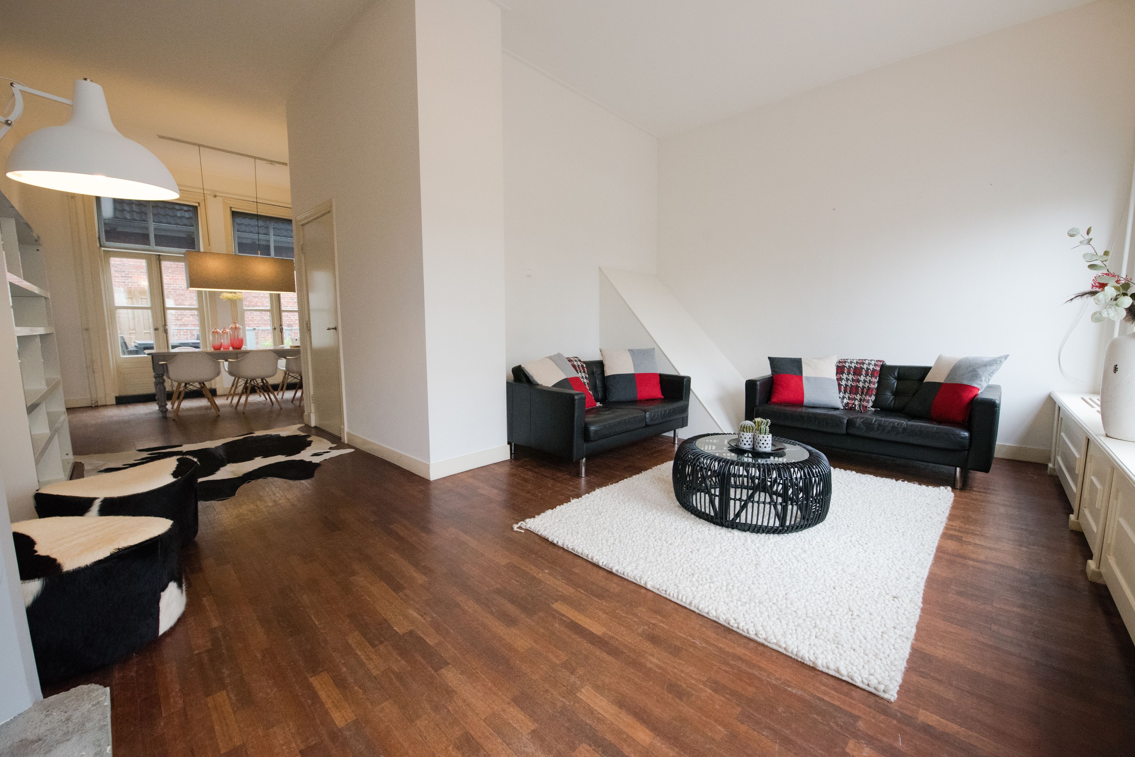 A modern living room with a black sofa, white rug, and a coffee table.