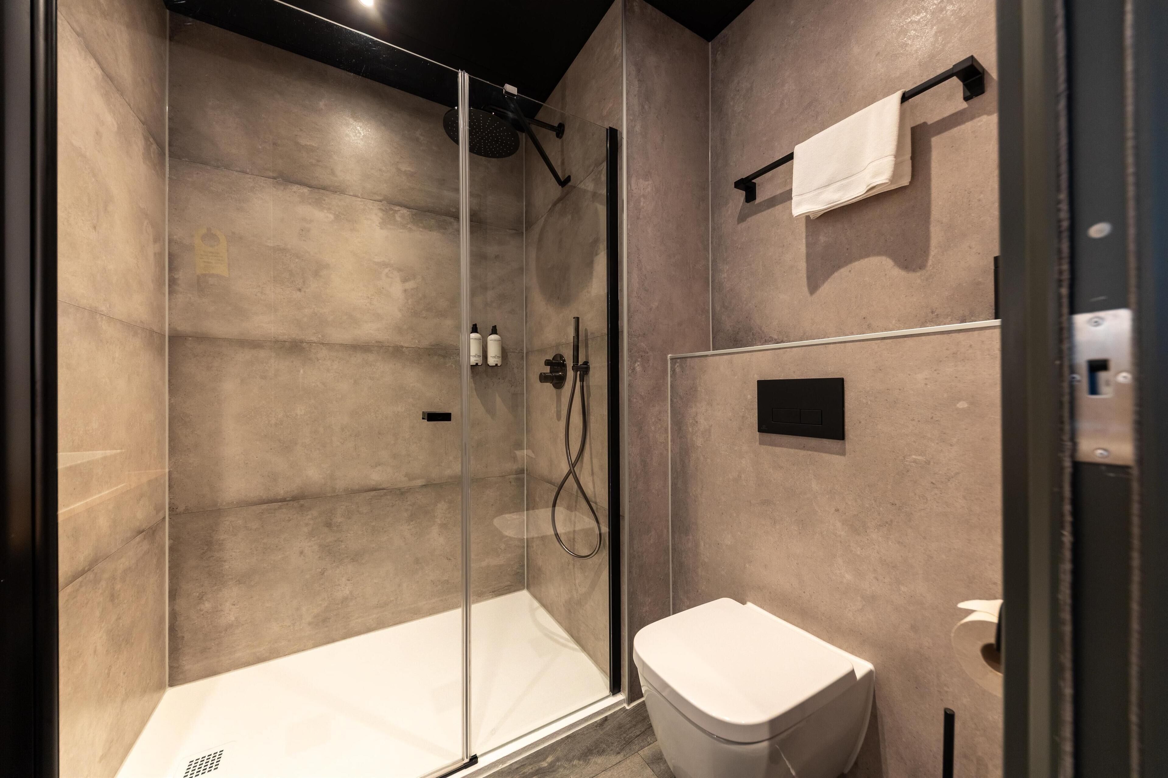 A modern bathroom with a glass-enclosed shower, a toilet, and a towel rack.