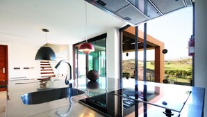 A modern kitchen with a large island, stainless steel appliances, and a pendant light. - Villas Salobre (San Bartolome de Tirajana)