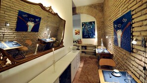 A dining area with brick walls, wooden furniture, and artwork.