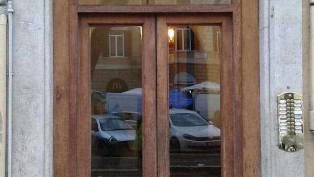 A double wooden door with glass panels, a small overhang, and a metal kick plate.
