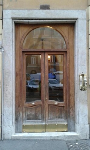 A double wooden door with glass panels, a small overhang, and a metal kick plate. - Caesar's Rooms (Rome)