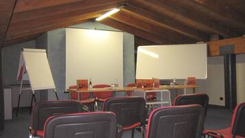 A conference room with red chairs, a whiteboard, and a projector screen.