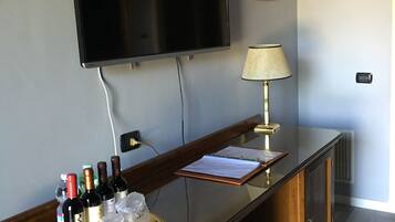 Eine Barbereich mit einem Flachbildfernseher, einer Lampe und einem Tablett mit Flaschen und Gläsern.