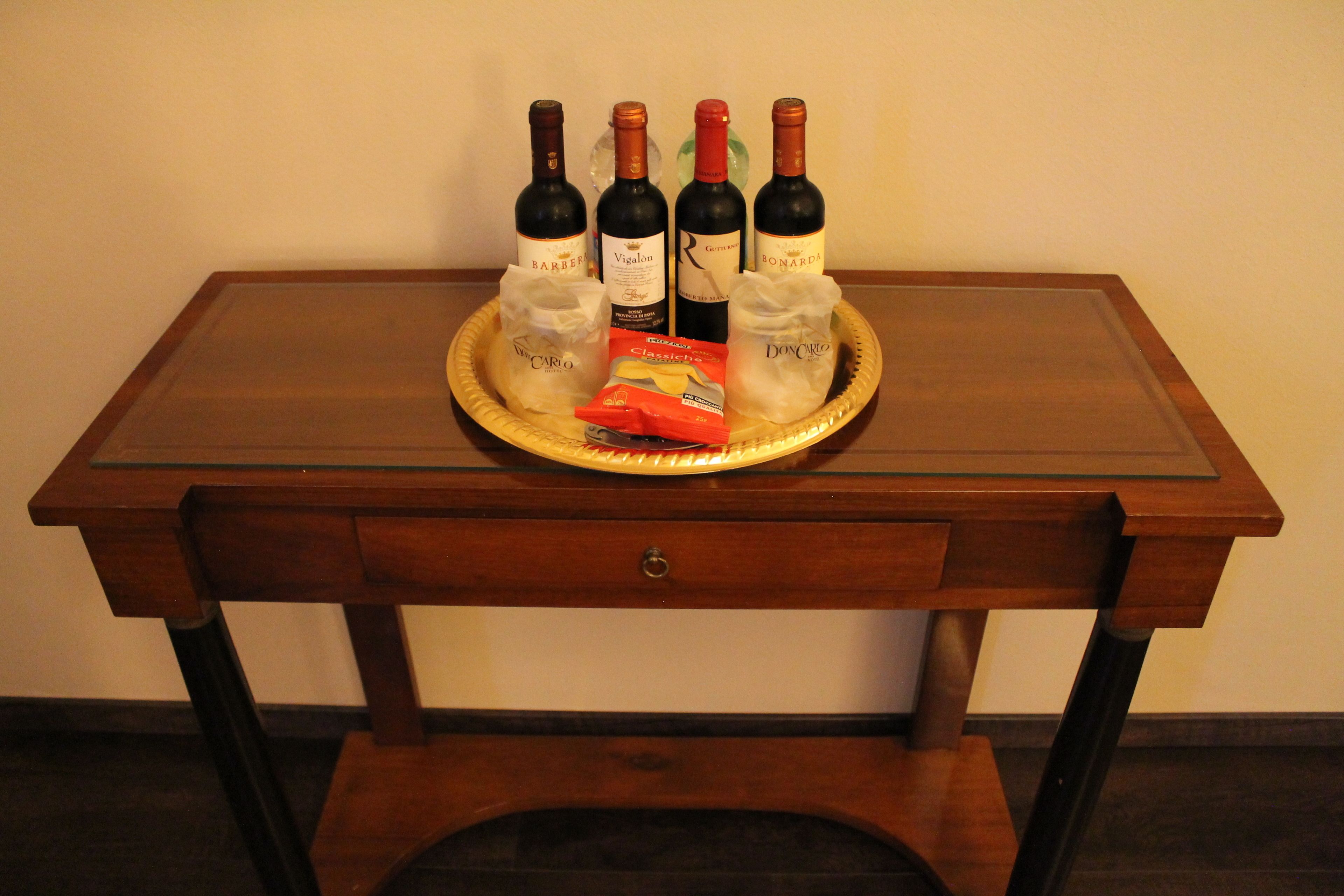 A wooden table with four wine bottles and a packet of snacks.
