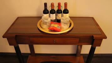 A wooden table with four wine bottles and a packet of snacks.