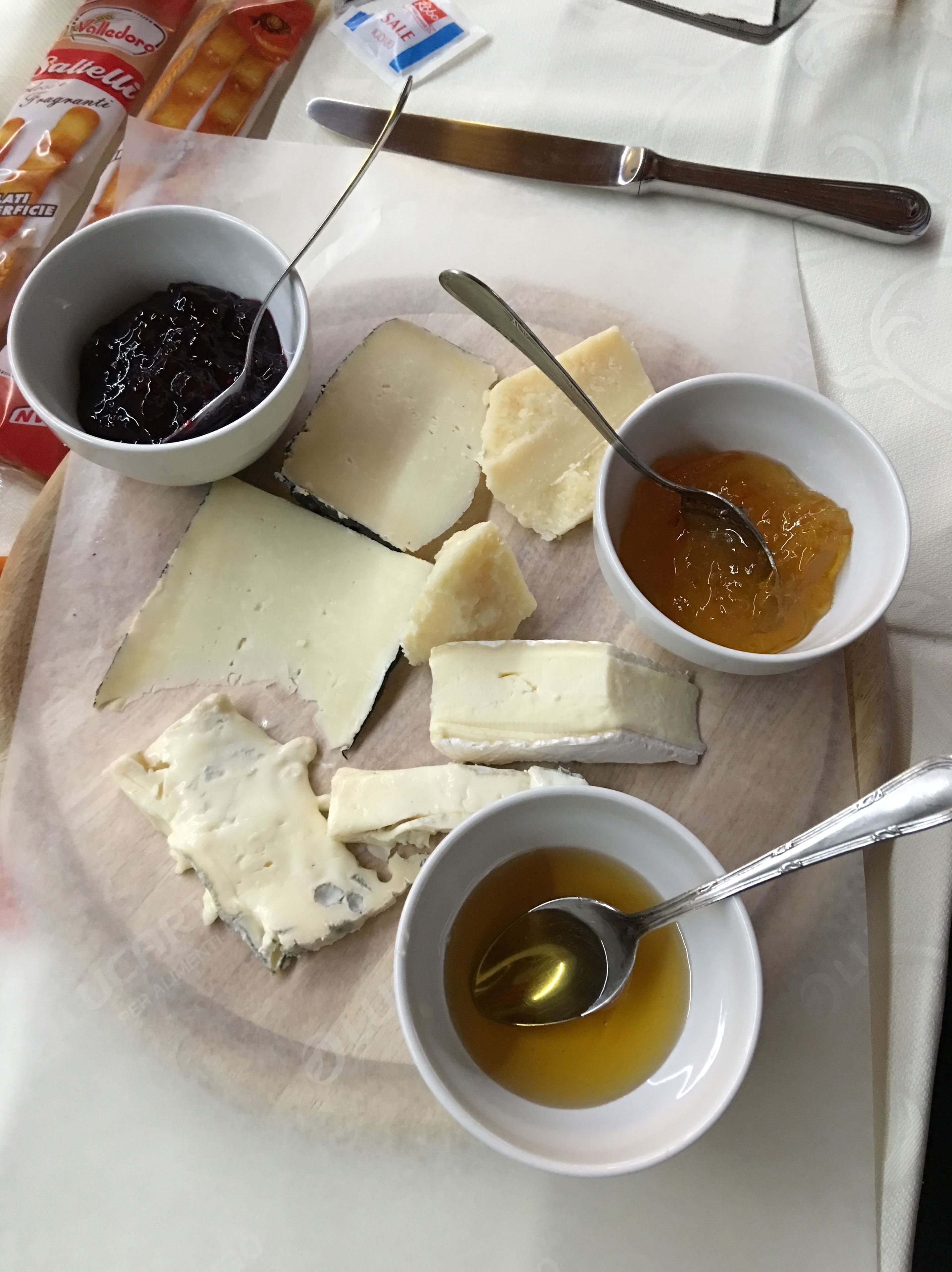 A cheese platter with various cheeses and accompaniments on a wooden board.