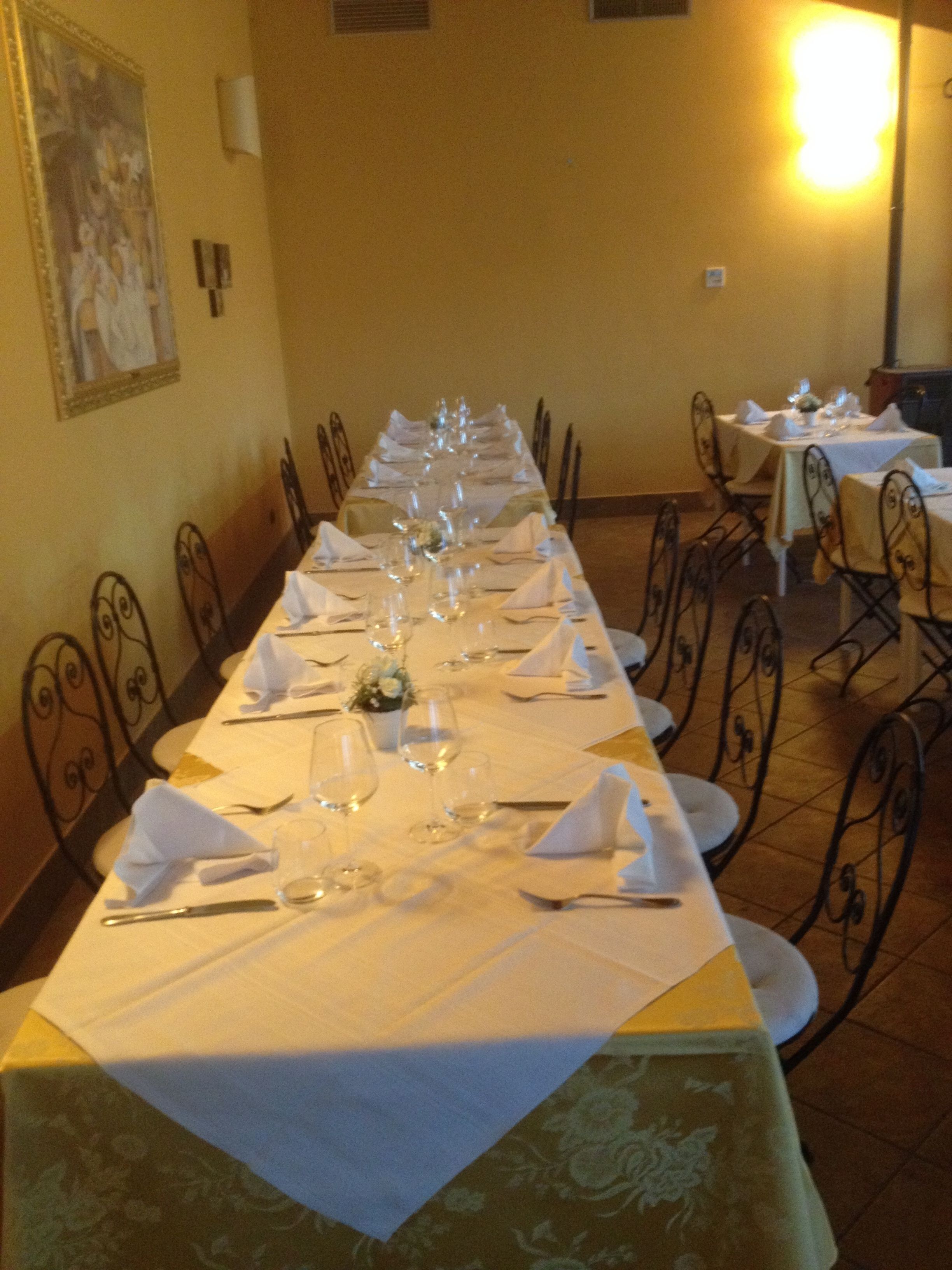 Una larga mesa de comedor lista para una comida en una habitación con sillas y mesas.