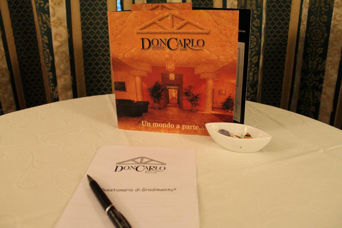 A brochure for DonCarlo Hotel with a view of the entrance and a bowl of fruit on the table.