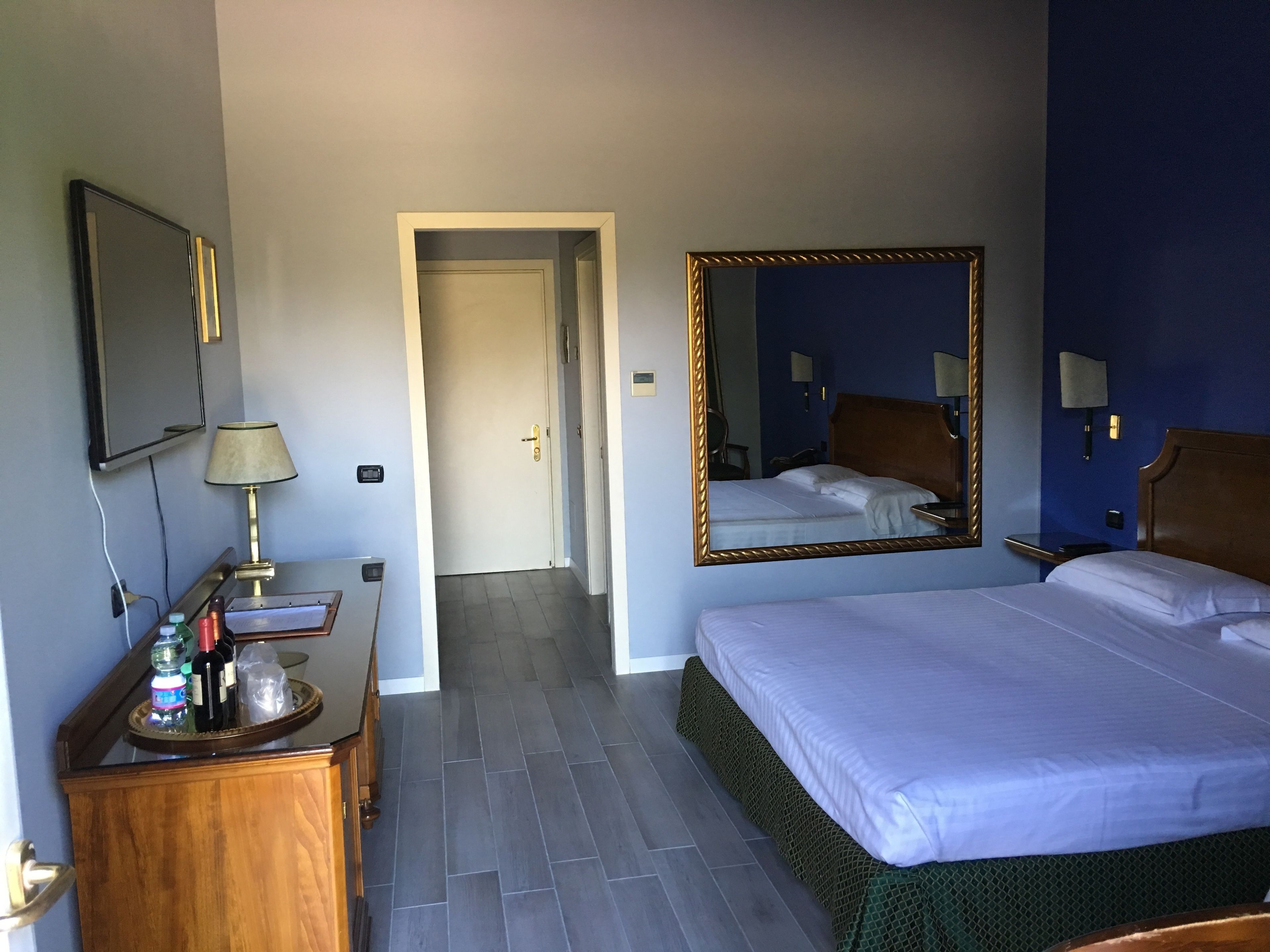 Une chambre d’hôtel avec un lit, une commode, un miroir et un téléviseur.