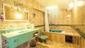A bathroom with a green sink, a toilet, a bathtub, and a shower area.