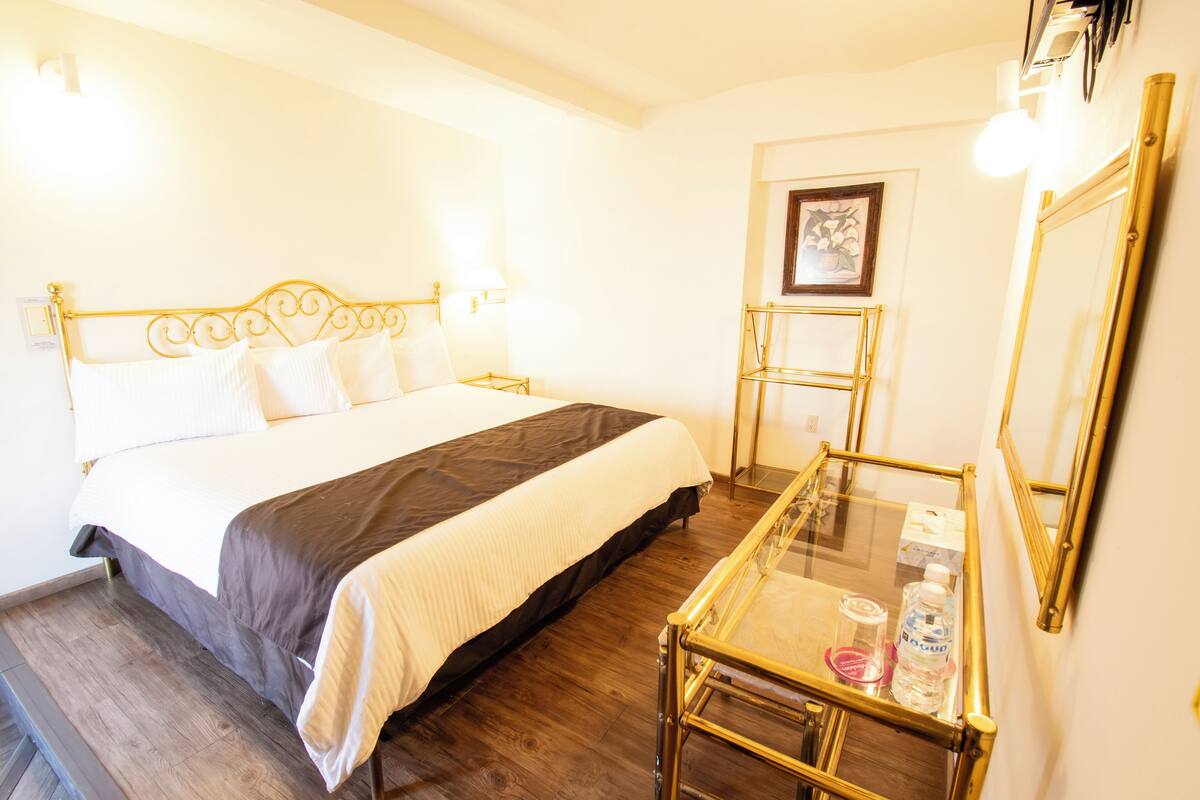 Una habitación de hotel con cama, mesita de noche y espejo.