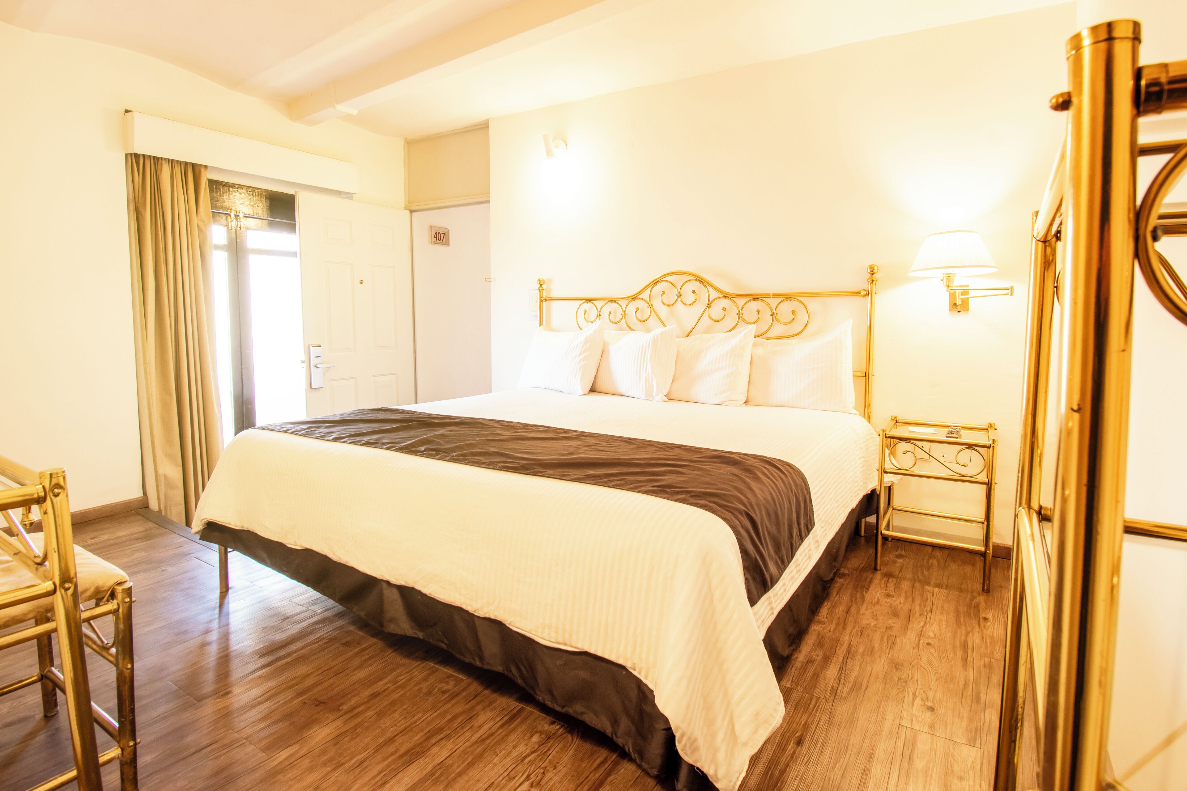 Une chambre d’hôtel avec un grand lit, une table de chevet, une chaise et une porte.