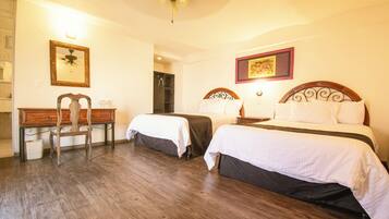 A hotel room with two beds, a desk, a chair, a ceiling fan, and a shower area.