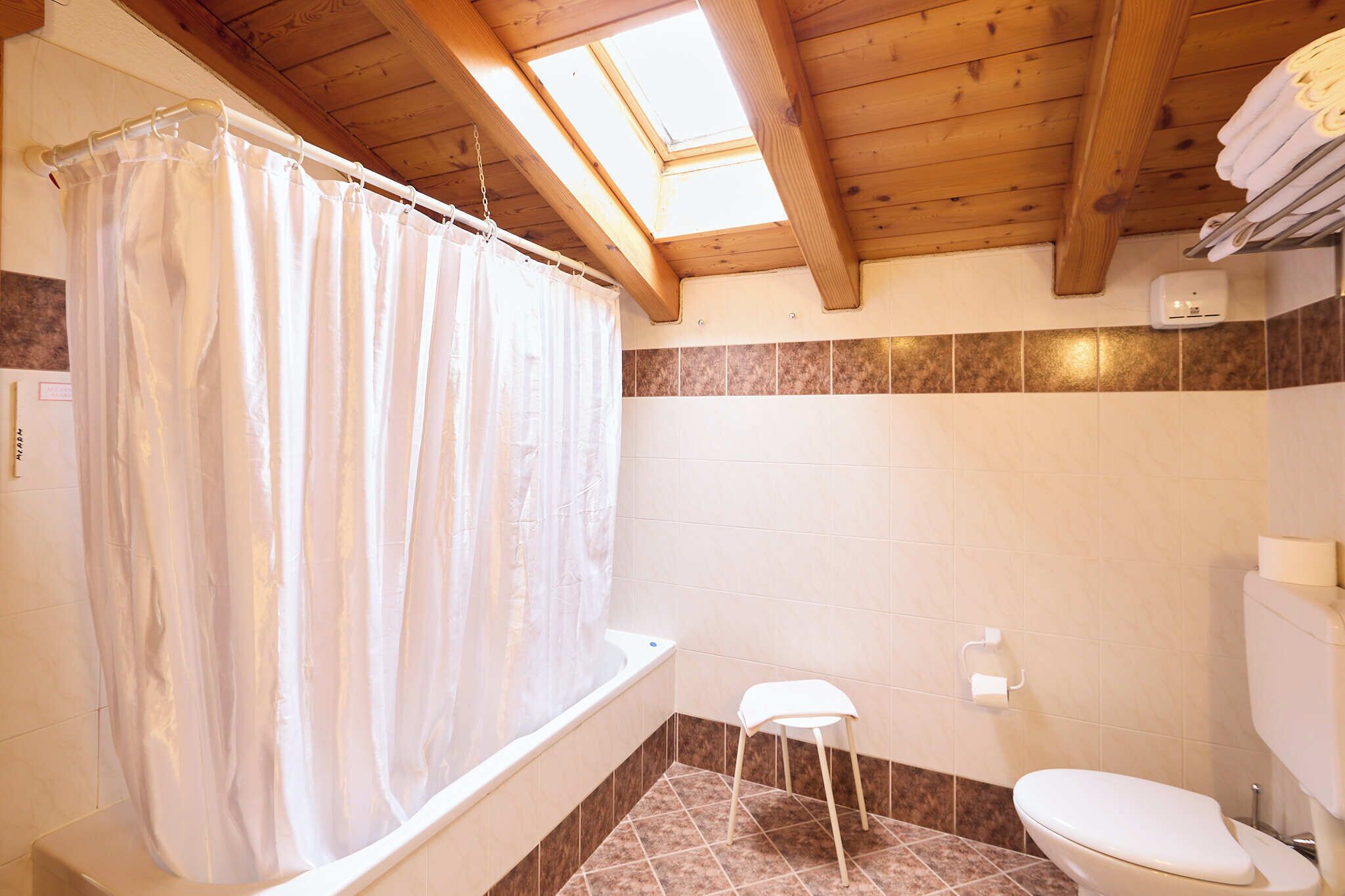 A bathroom with a bathtub, toilet, and a small stool.