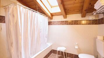 A bathroom with a bathtub, toilet, and a small stool.