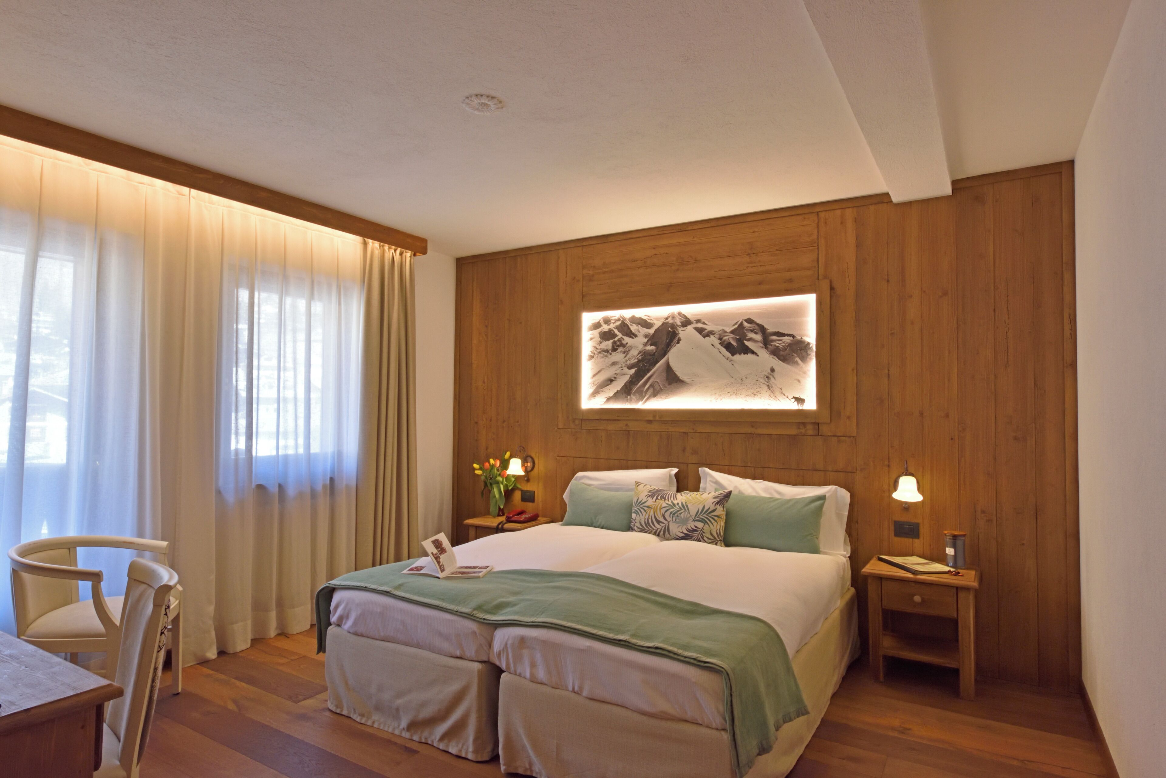 A bedroom with a bed, bedside tables, a chair, and a wall-mounted picture.