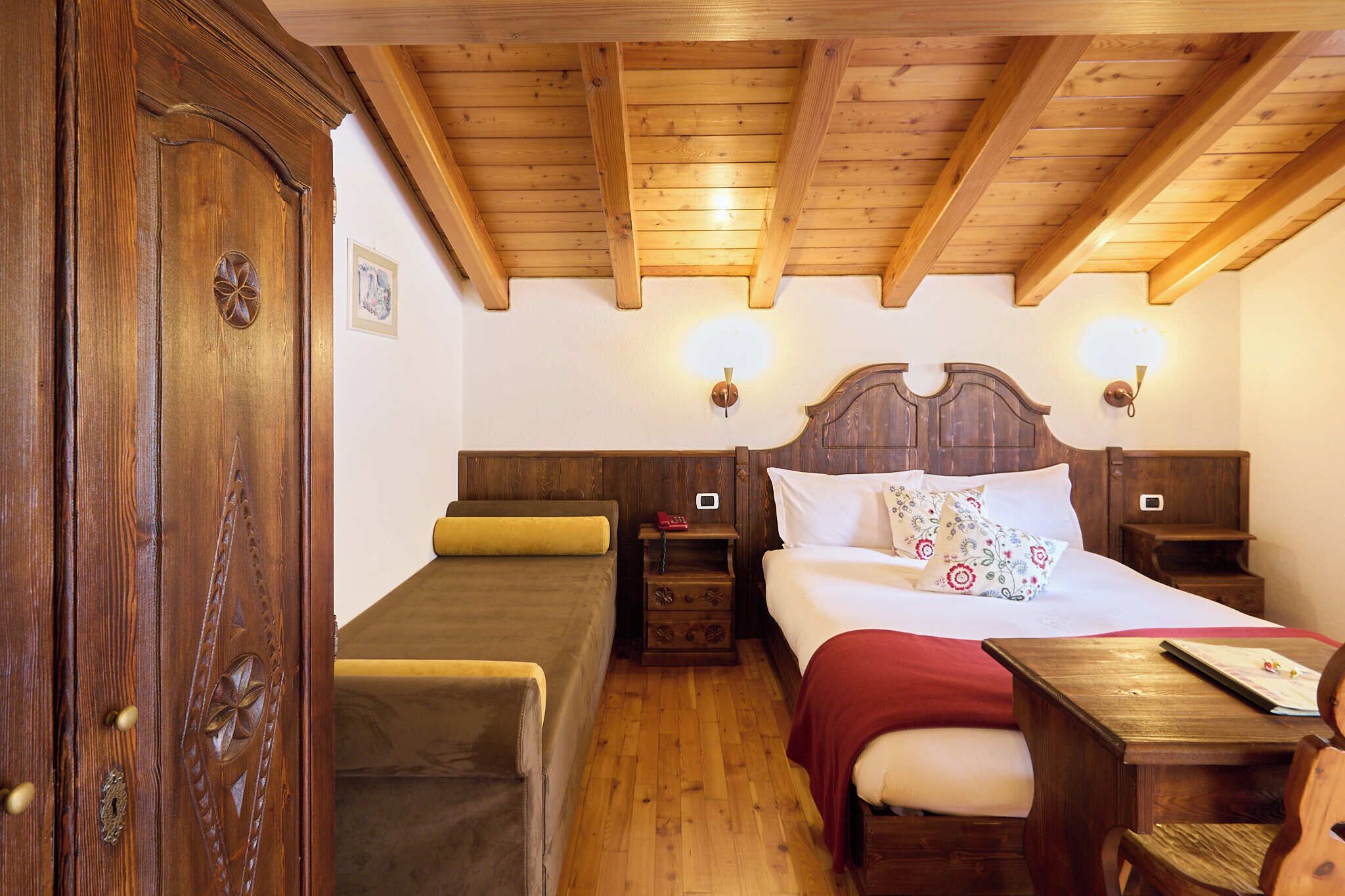 Una stanza in legno con un letto matrimoniale, due letti singoli, un tavolo in legno e una porta.