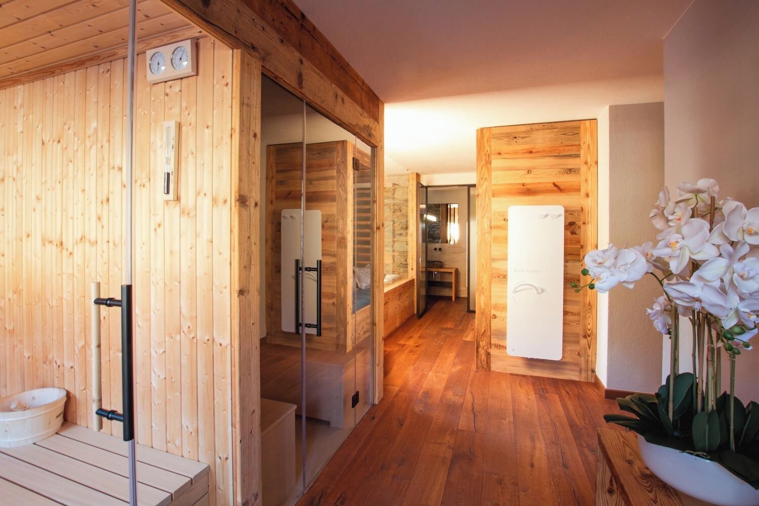 A wooden interior with a sauna, a wooden bench, and a potted orchid.