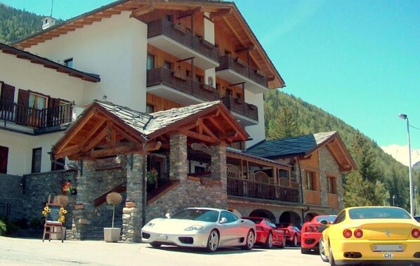 A multi-story building with balconies, a stone facade, and a wooden roof structure. - Hotel Beau Sejour (Etroubles)