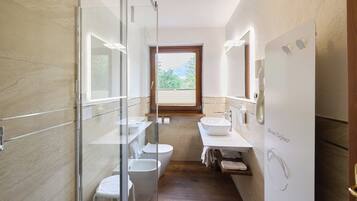 Un bagno moderno con cabina doccia in vetro, un water, un bidet e un lavabo con specchio.