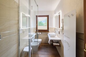 A modern bathroom with a glass shower enclosure, a toilet, a bidet, and a sink with a mirror. - Hotel Beau Sejour (Etroubles)