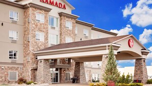 Un hotel Ramada con fachada de piedra, múltiples ventanas y un acceso cubierto.