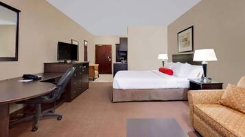 A hotel room with a bed, a desk, a chair, a sofa, and a TV.
