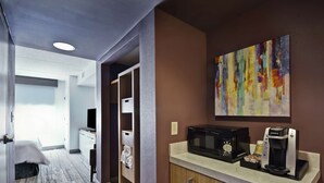 Ein Hotelzimmer mit einer Küchenzeile, einer Mikrowelle, einer Kaffeemaschine und einem Bild an der Wand.