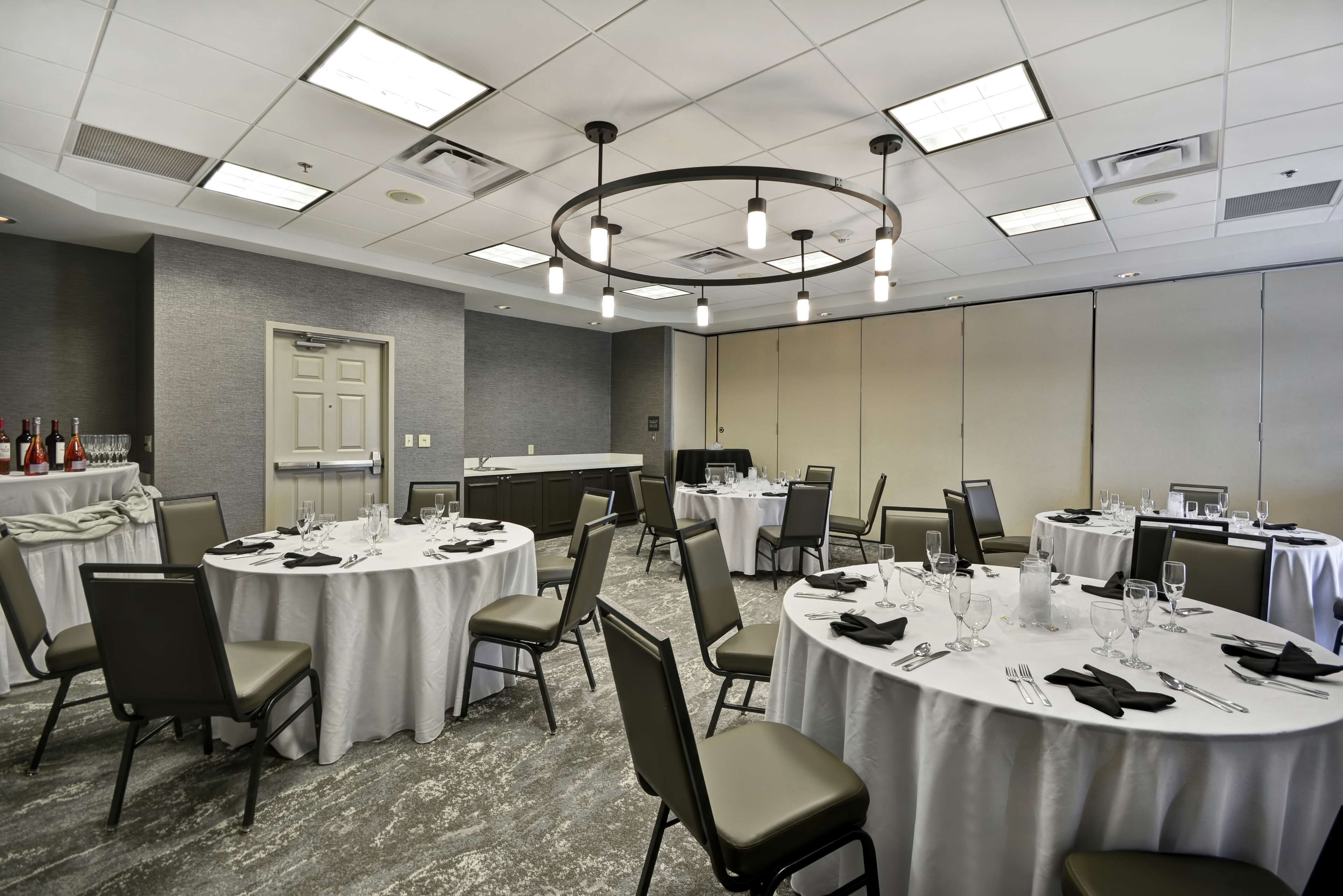 A conference room with multiple round tables, each set with chairs and dining essentials.