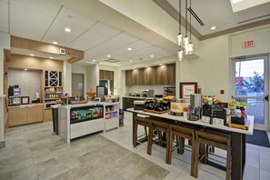 Un interno di caffetteria moderna con un bancone, una zona salotto e diversi prodotti alimentari in mostra.