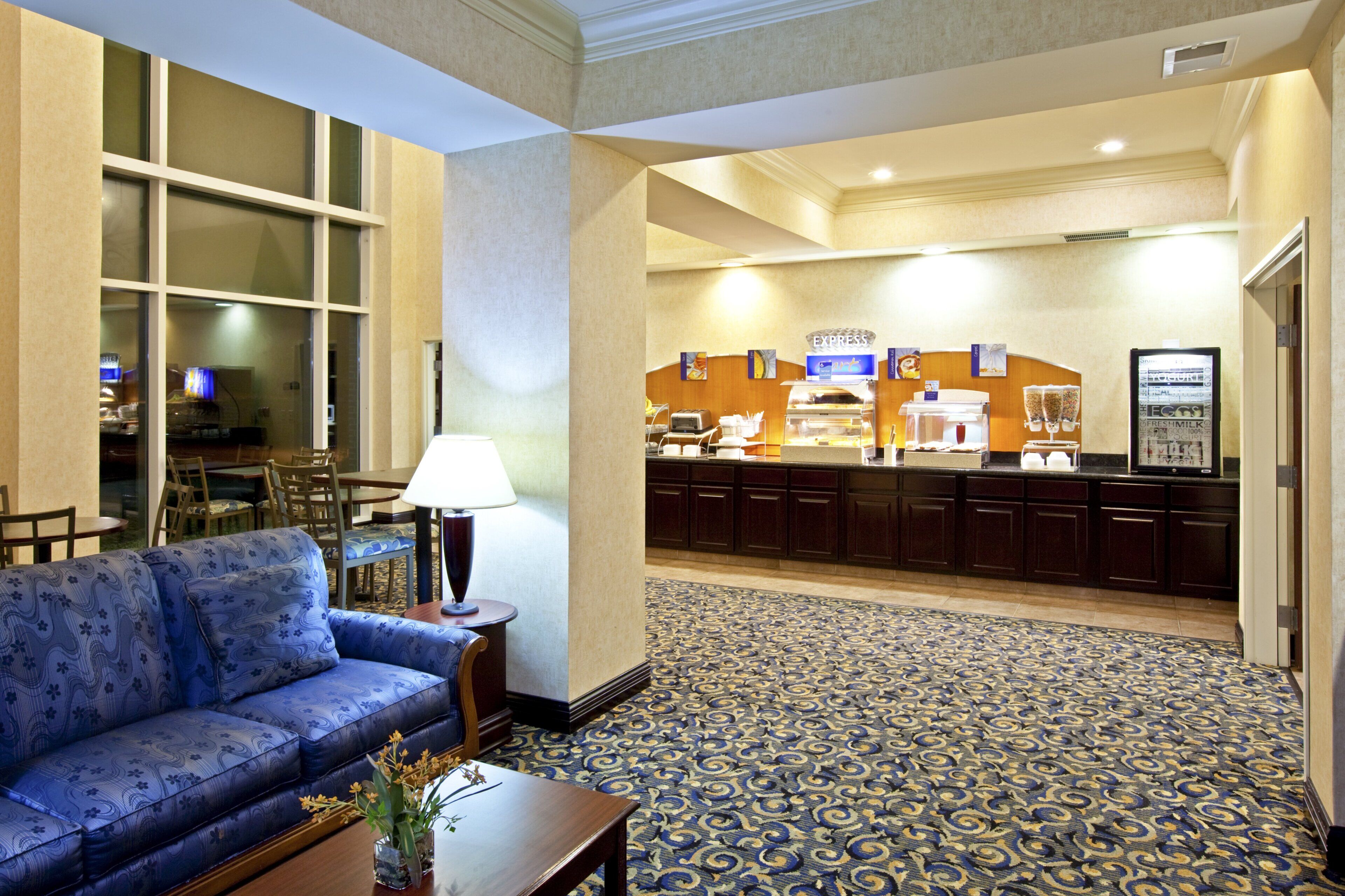 Una hall d'albergo con reception, divano, tavolino da caffè e tappeto decorato.