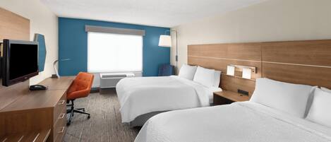 A hotel room with two beds, a desk with a TV, a chair, a window, and a lamp.