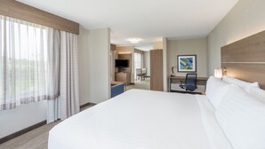 Ein Hotelzimmer mit einem großen Bett, einem Schreibtisch mit Stuhl, einem Fernseher und einem Gemälde an der Wand.