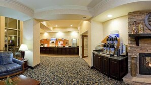 A lobby with a reception desk, a fireplace, and a seating area with a sofa and a lamp. - Holiday Inn Express Hotel & Suites Frankfort by IHG (Frankfort)