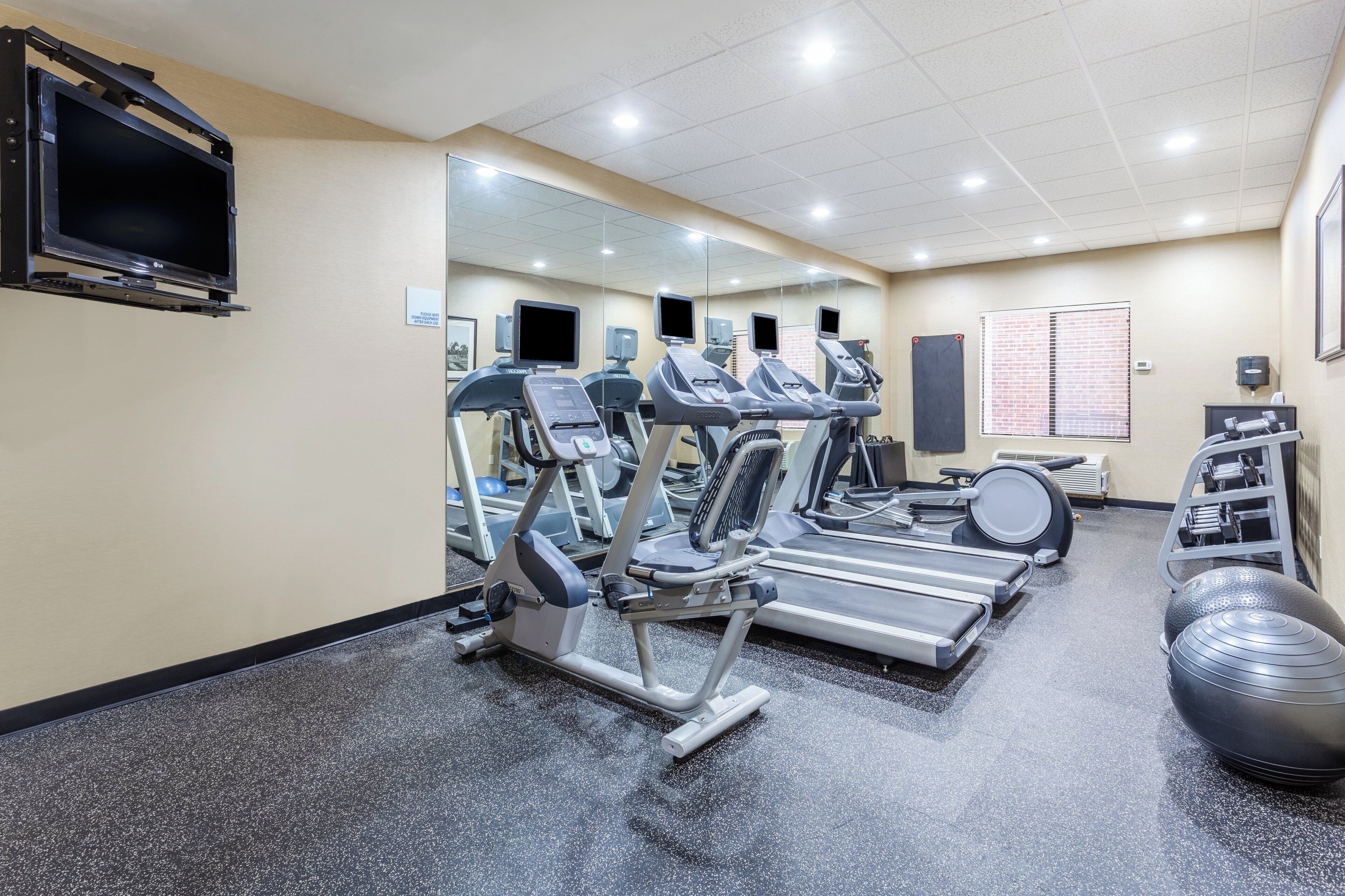 Un gimnasio con cintas de correr, elípticas y una bicicleta estática.