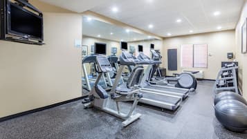 Un gimnasio con cintas de correr, elípticas y una bicicleta estática.